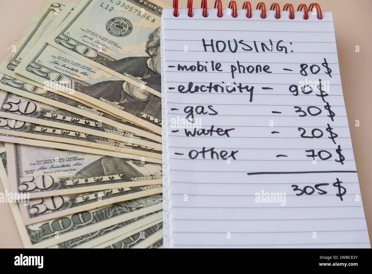 Bargeld in Dollar mit handgeschriebenen Wohnkosten für Notebooks. Rechnungen für Strom, Gas, Wasser zählen. Konzept des effizienten Verbrauchs und der Wirtschaftlichkeit. Ausgabegewohnheiten Stockfoto