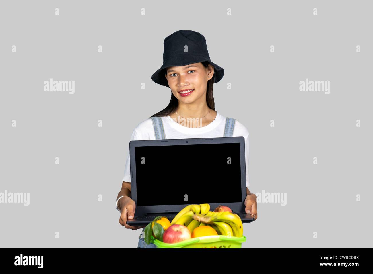 Ein Landwirt-Unternehmermädchen mit Obst und Gemüse mit Technik-Laptop und mit Ausdrücken und Gesten Stockfoto