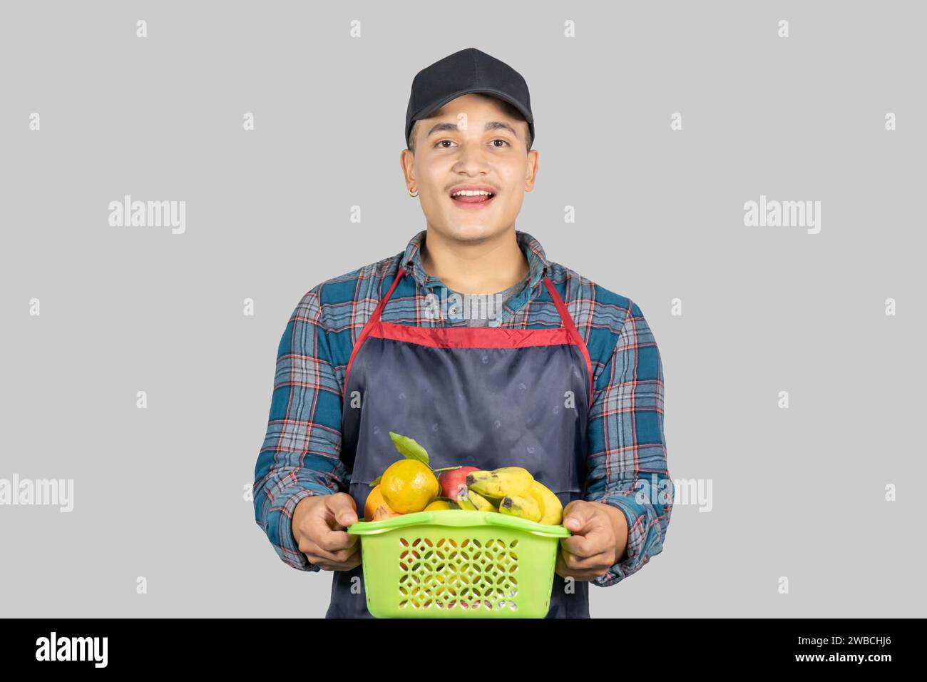 Junger asiatischer muskulöser und gesunder männlicher Farmer, der mit Obst- und Obstkorb Bio Lifestyle fördert Stockfoto