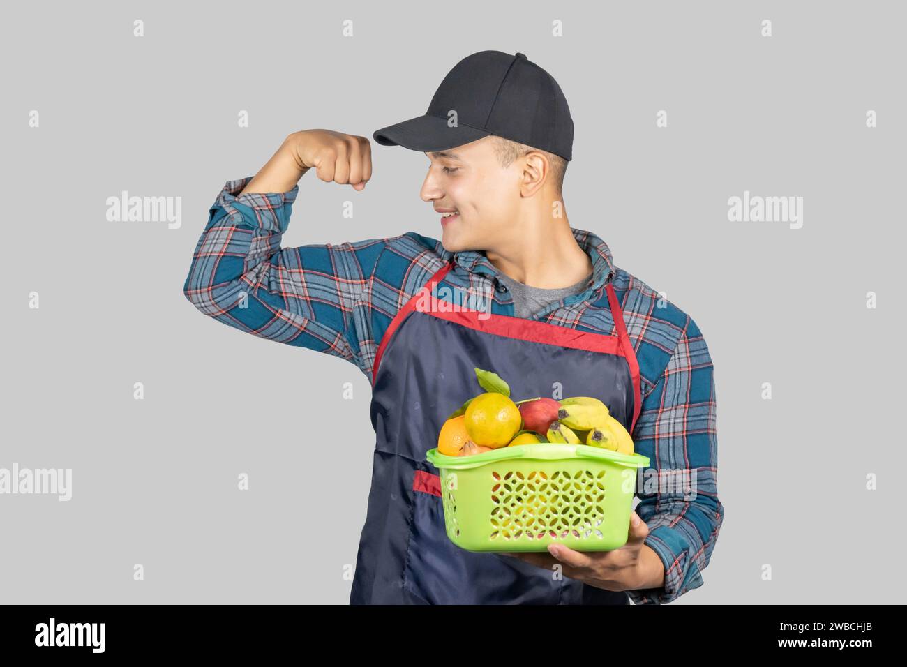 Junger asiatischer muskulöser und gesunder männlicher Farmer, der mit Obst- und Obstkorb Bio Lifestyle fördert Stockfoto