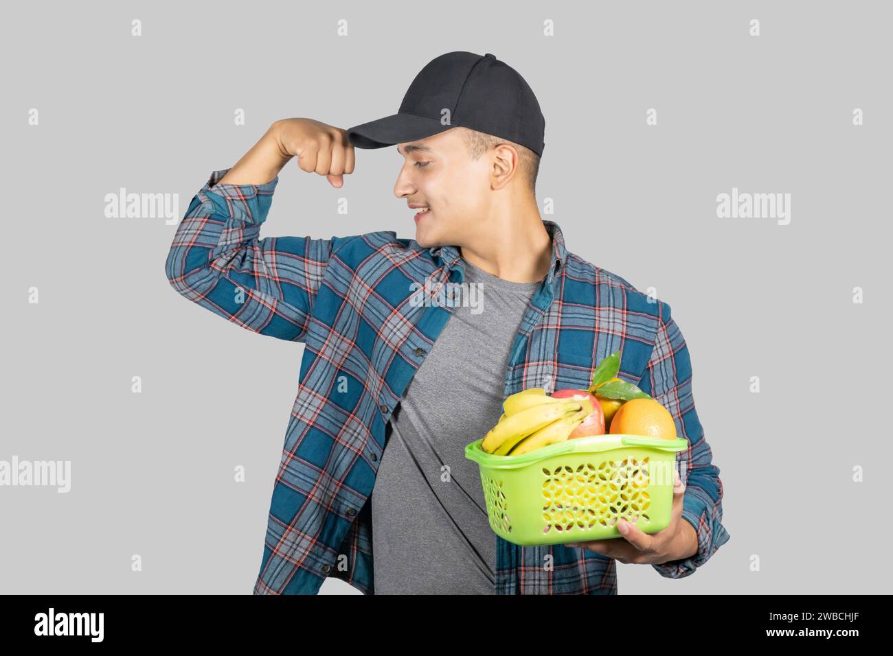 Junger asiatischer muskulöser und gesunder männlicher Farmer, der mit Obst- und Obstkorb Bio Lifestyle fördert Stockfoto