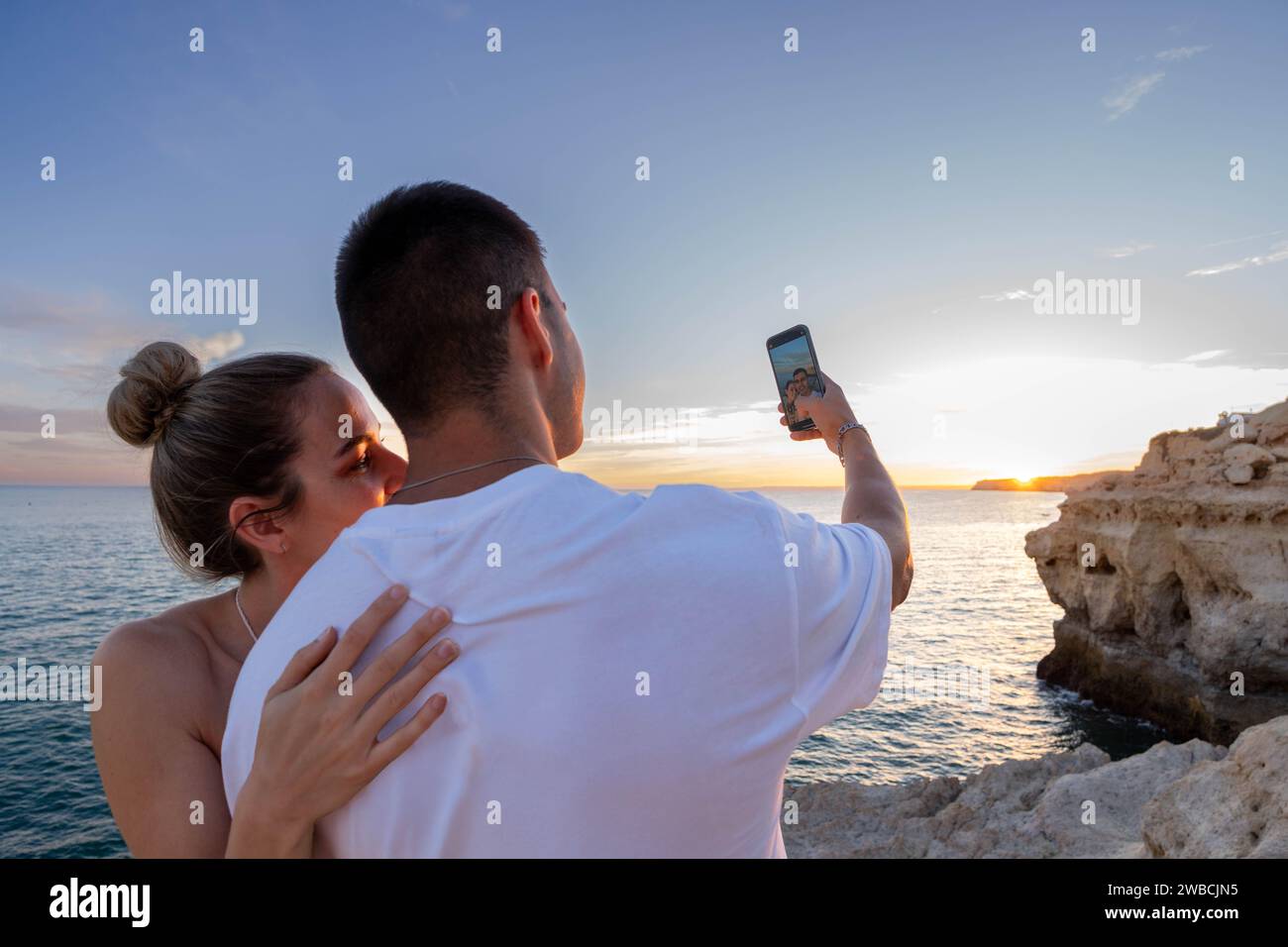 Ein junges Paar Selfie bei Sonnenuntergang am Strand: Ein Nahaufnahme von hinten Stockfoto