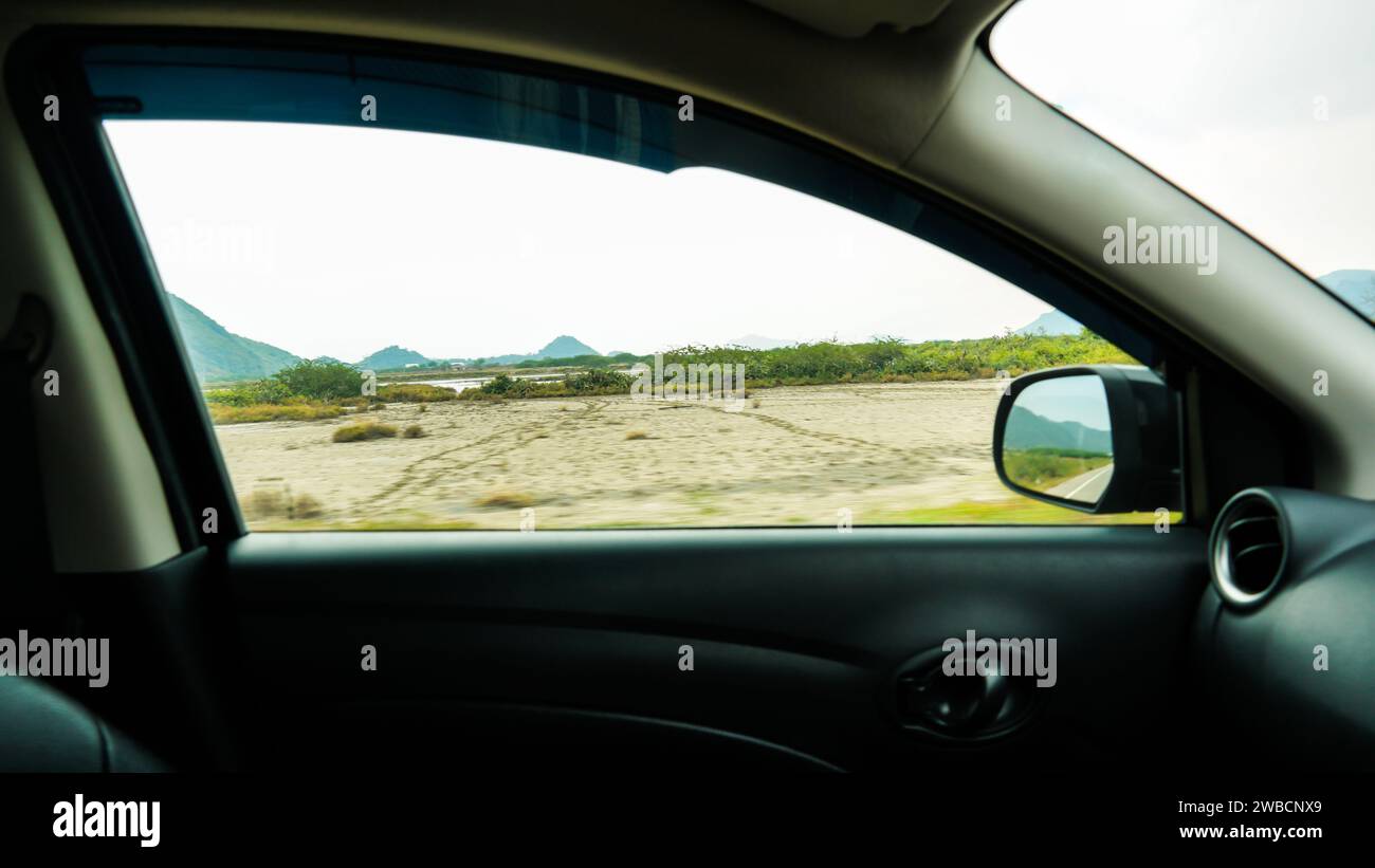 Blick in das Seitenfenster eines Autos während der Fahrt auf der Landstraße. SideView-Fahrzeugspiegel des Beifahrers. Reise und Reise. Stockfoto