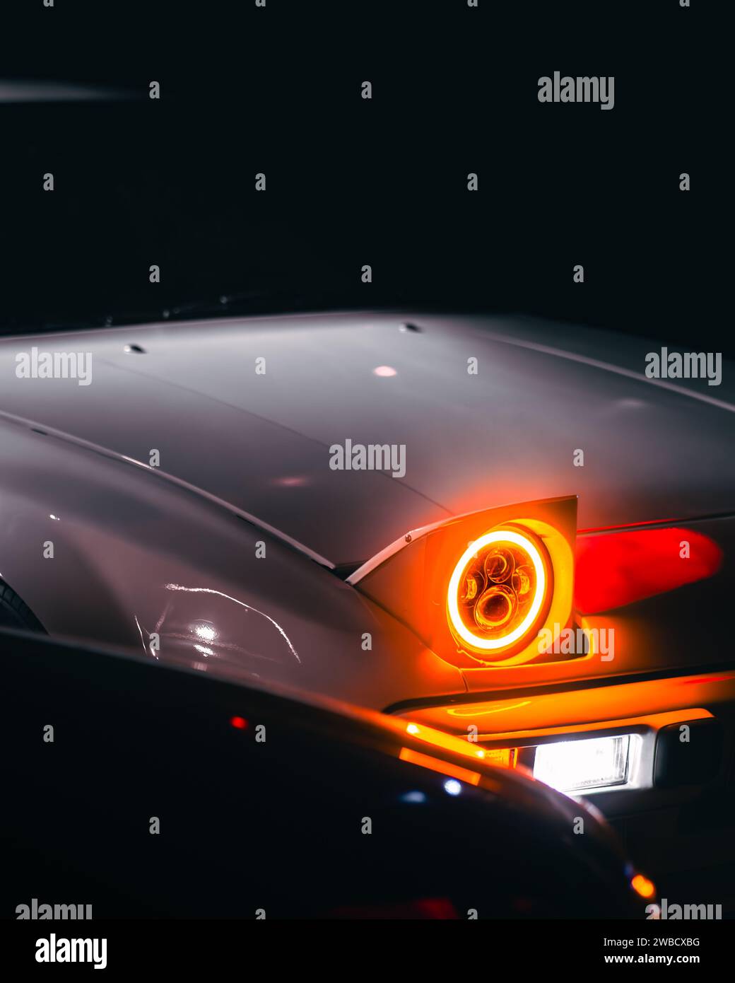 Ein Auge oder ein Licht, vielleicht beides: Eine Nahaufnahme des Scheinwerfers eines Autos, der wie ein Auge aussieht Stockfoto