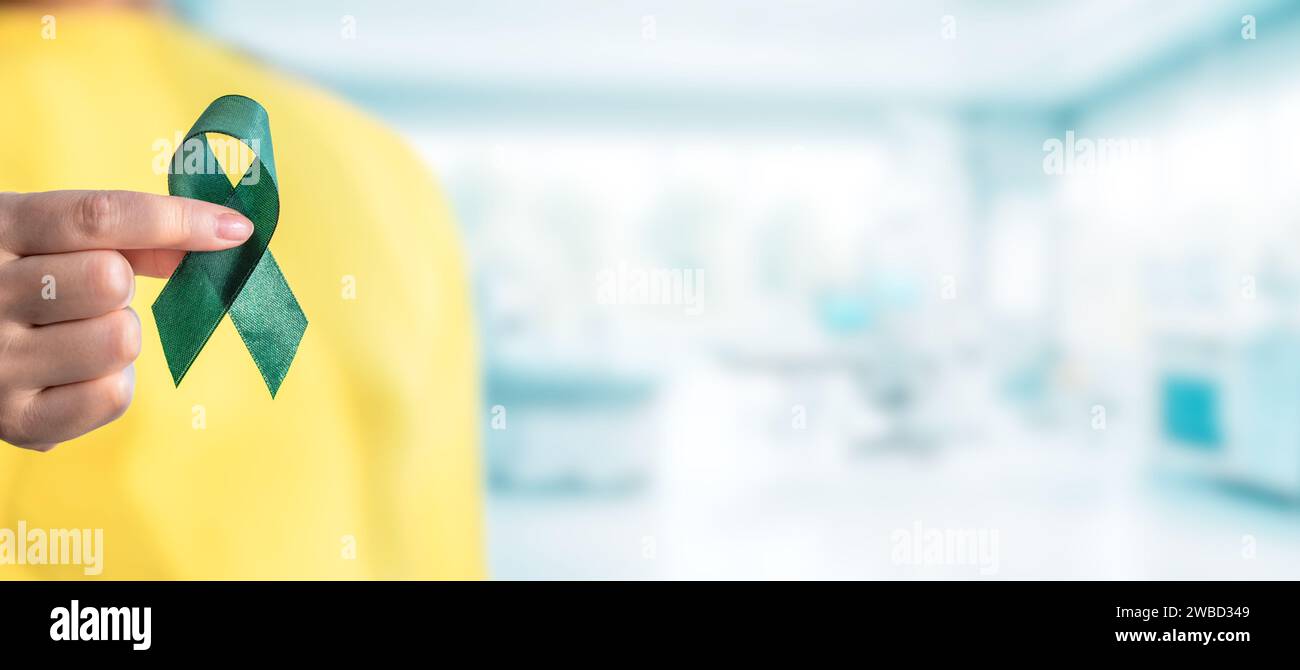 Gesundheitswesen und Weltkrebstag Konzept. Das grüne Band für die Unterstützung von Lebenspartnern halten Stockfoto
