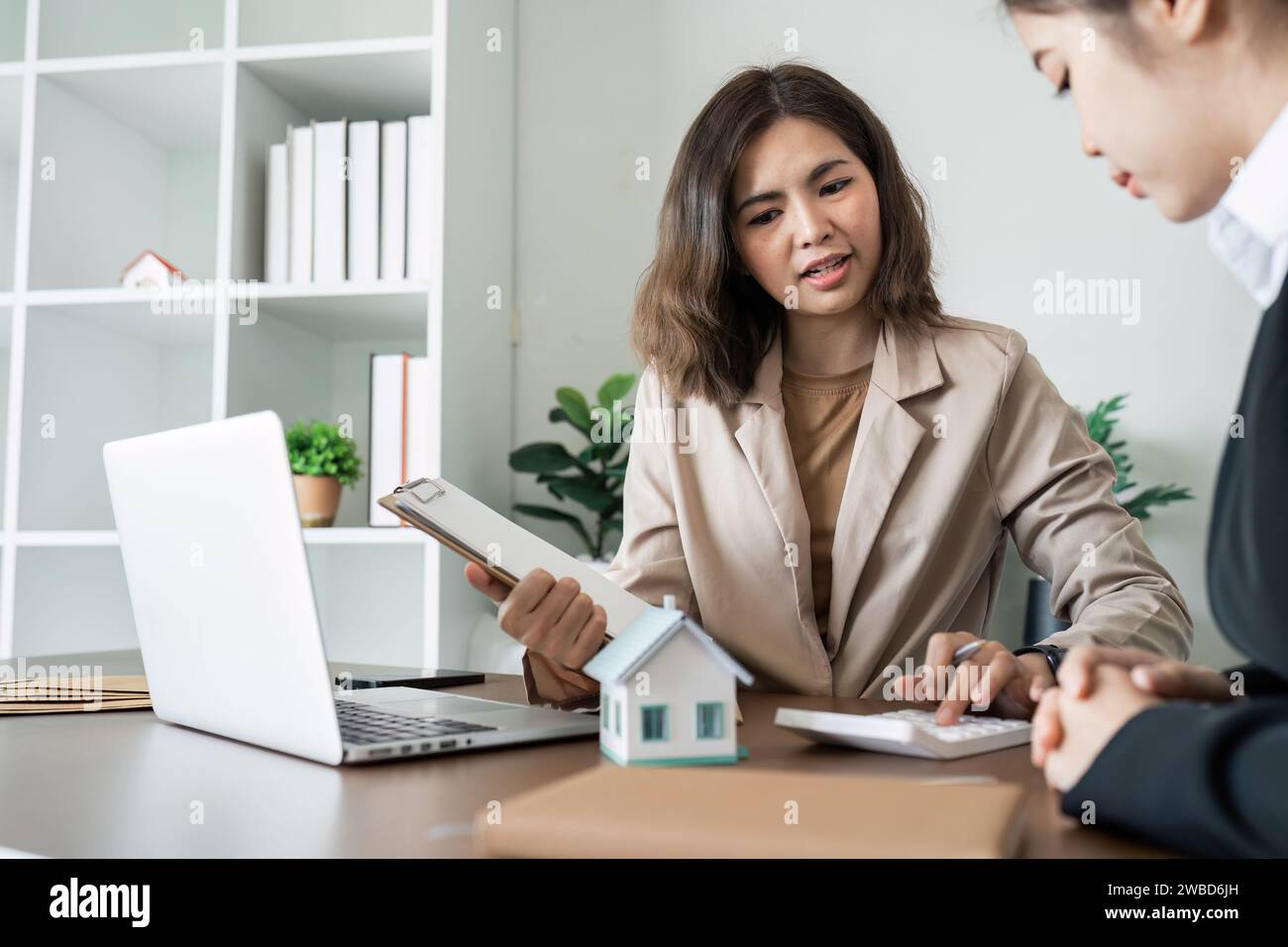 Immobilienmakler sprechen mit neuen Eigenheimkäufern und bieten gute Zinssätze an und berechnen Kunden auf Hypothekenfinanzierung Stockfoto