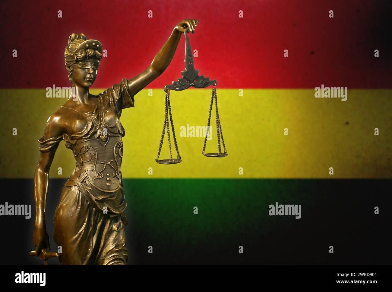 Nahaufnahme einer kleinen Bronzestatuette von Lady Justice vor einer bolivianischen Flagge. Stockfoto