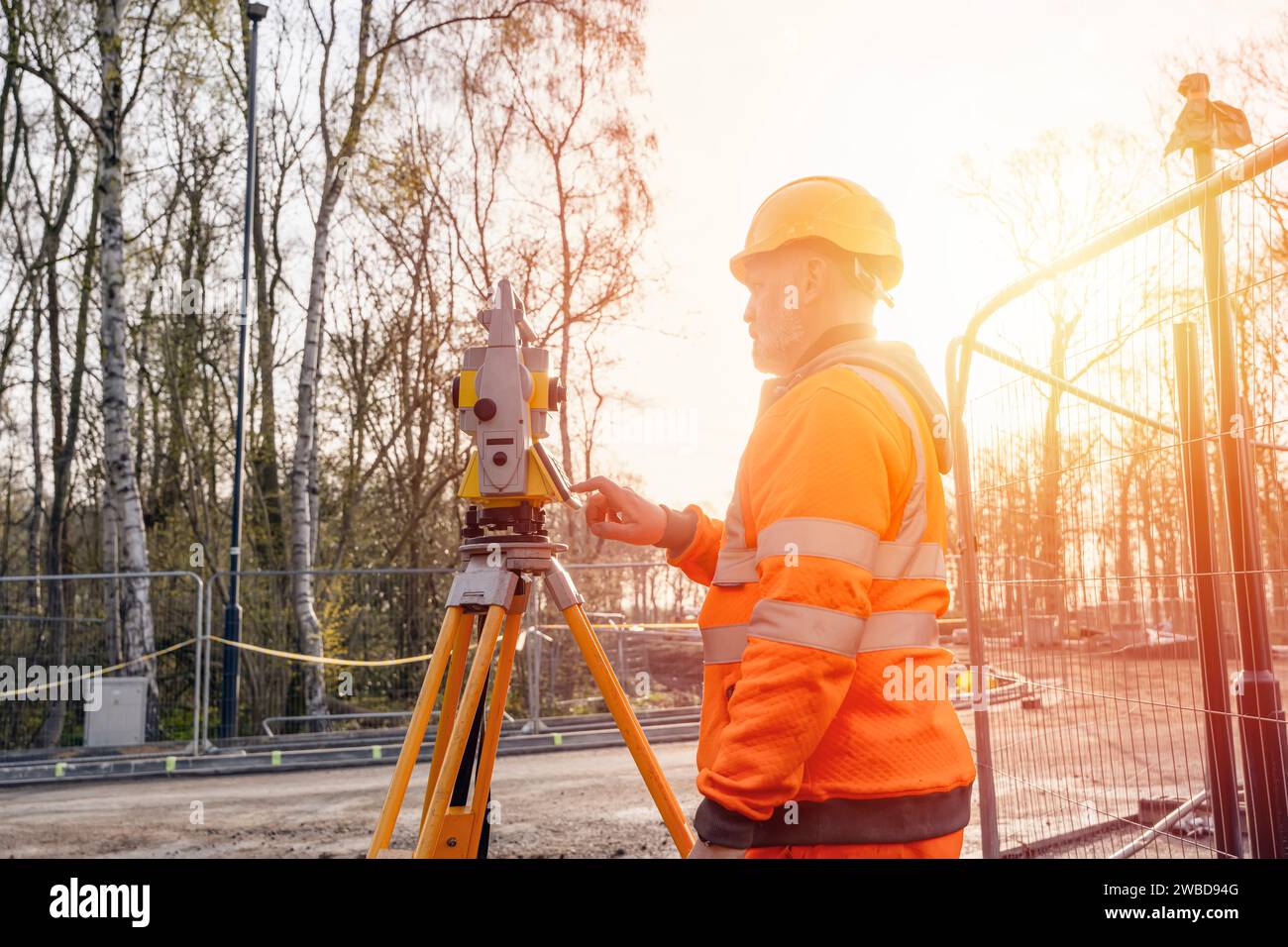 Der Bauingenieur stellt sein Gerät während der Bauarbeiten ein. Bauherr, der Tachymeter für die Gesamtpositionierung auf der Baustelle für die neue Straße setti installiert Stockfoto