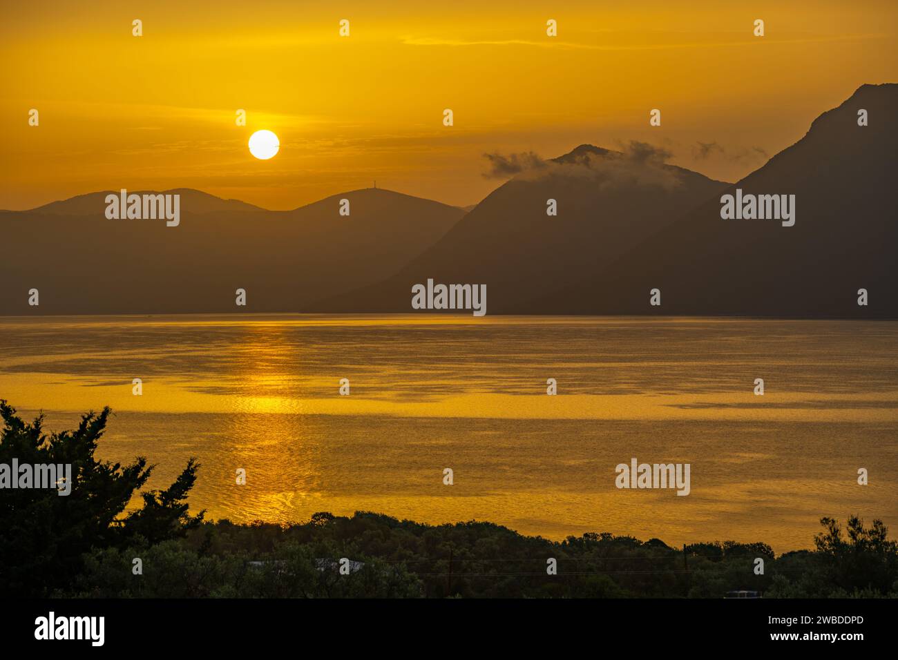 Sonnenaufgang hinter den Bergen des griechischen Festlandes von der Insel Meganisi im Ionischen Meer Stockfoto