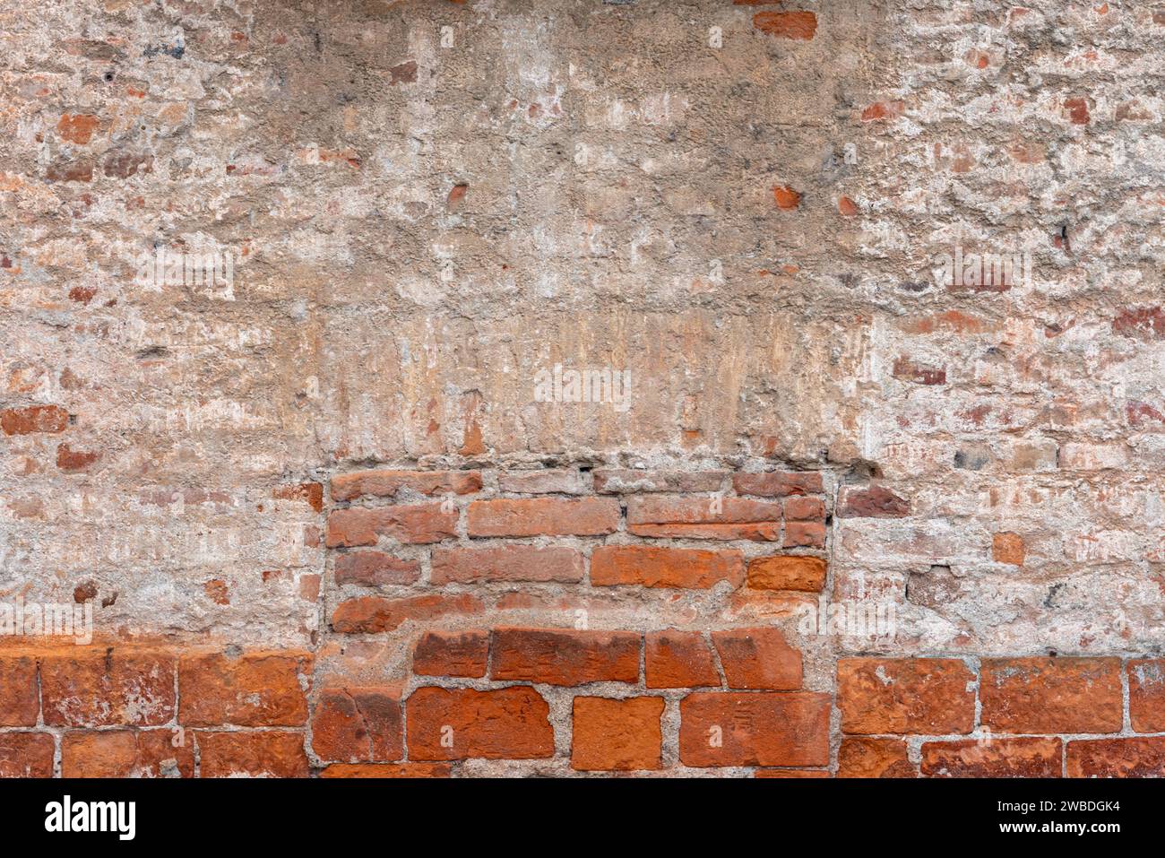 Alte Wandstruktur mit Putz und abblätterndem Hintergrund mit freiliegendem Ziegelstein. Hintergrund der Mauer mit Gips und Ziegeln und ummauertes Fenster mit Ziegeln. Ideal Stockfoto