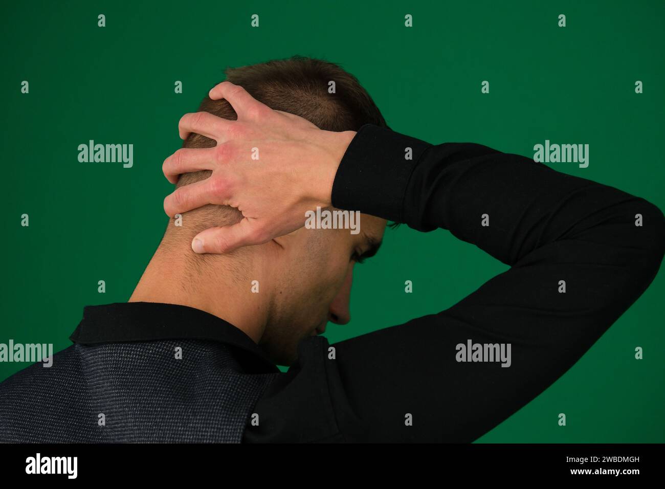 Emotionen eines gutaussehenden Mannes auf grünem Hintergrund Chromakey Nahaufnahme dunkles Haar junger Mann junger Geschäftsmann auf einem Schreibtisch, mit einem gelangweilten Ausdruck. Hochwertige Fotos Stockfoto