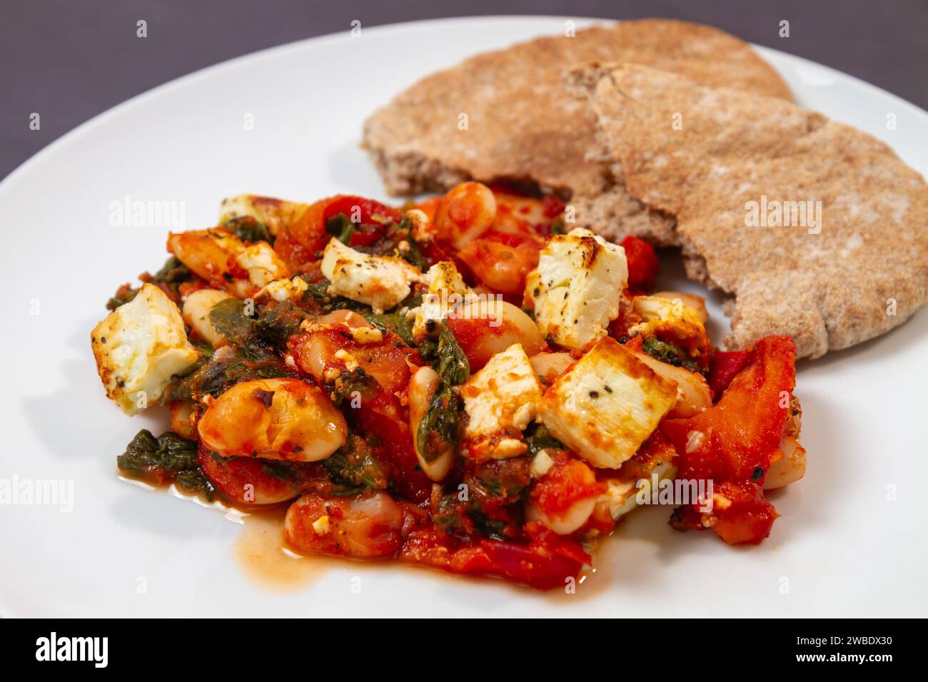 Knusprig gegrillter Feta mit sautigen Butterbohnen und Pitta-Brot Stockfoto