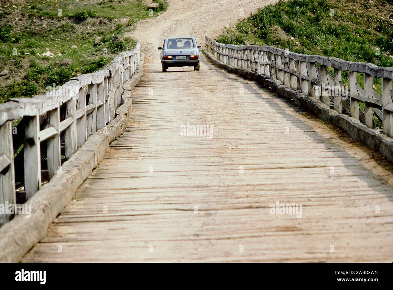 Vrancea County, Rumänien, ca. 1975. Ein Dacia-Fahrzeug, das über die alte Holzbrücke zum Dorf Poduri fährt. Stockfoto