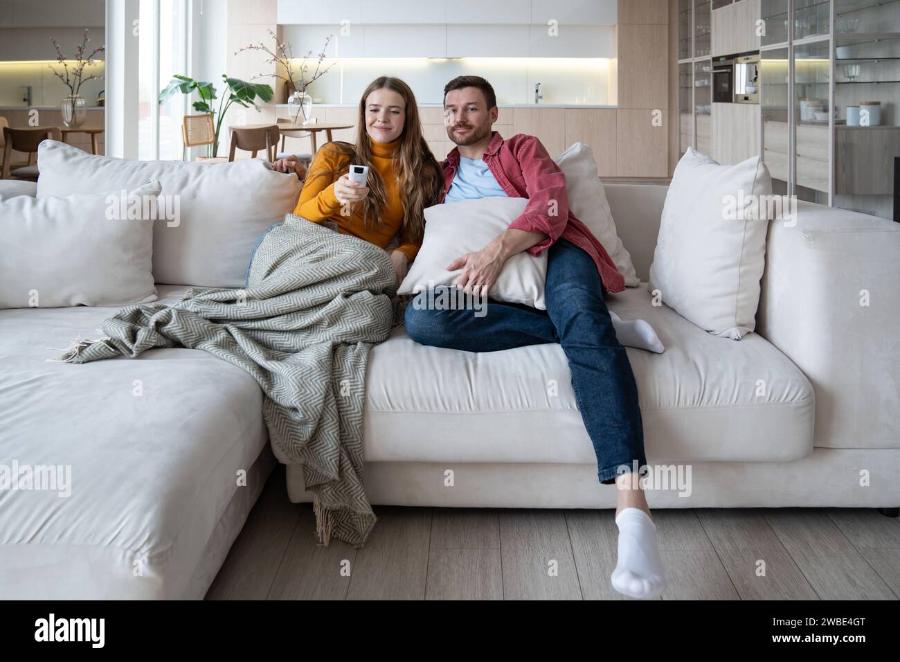 Ein entspanntes Familienpaar sieht zusammen auf einem gemütlichen Sofa zu Hause fern und genießt Lieblingsfilme Stockfoto