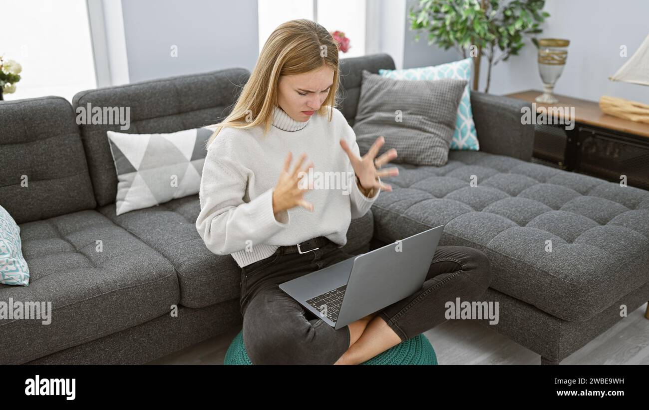 Frustrierte Frau mit Laptop im modernen Wohnzimmer Stockfoto