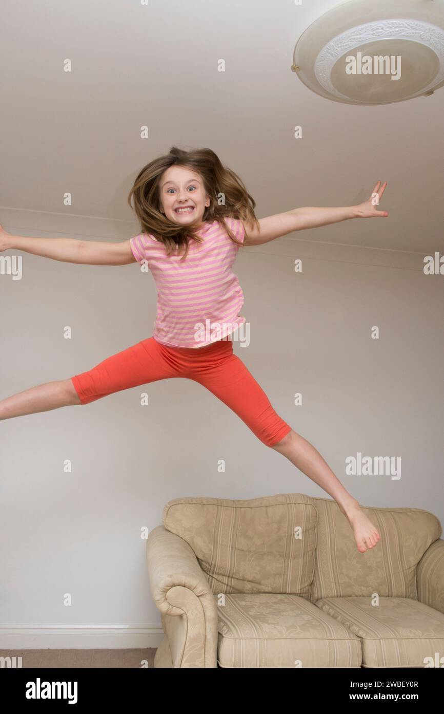 Kind, Mädchen im Haus hüpft, springt auf Möbel, Sofa, ist energiegeladen, hyperaktiv, Spaß haben, acht Jahre alt, Stockfoto