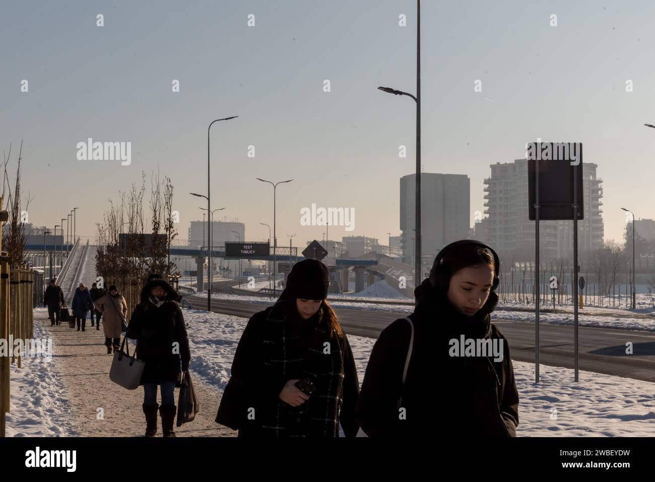 Krakau, Polen, 10. Januar 2024. Pendler laufen auf einem Bürgersteig im Norden Krakaus, während Luftverschmutzung über der Stadt zu sehen ist, während die Temperaturen deutlich unter 0 °C fielen. Die Luftverschmutzung wurde für sehr ungesund erklärt, und die PM2,5-Konzentration lag 30-mal höher als die jährlichen Luftqualitätsrichtlinien DER WHO. Die Verschmutzung ist eine Kombination aus Windmangel und niedrigen Temperaturen, die die Stadt und ihre Bewohner zwangen, ihre Häuser zu heizen. Stockfoto