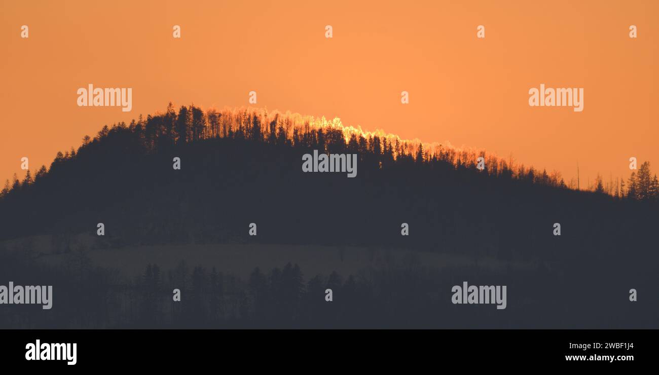 Wald auf dem Hügel und Sonnenuntergang im Hintergrund. Landschaft der Natur der Tschechischen republik. Romantischer farbenfroher Himmel. Stockfoto