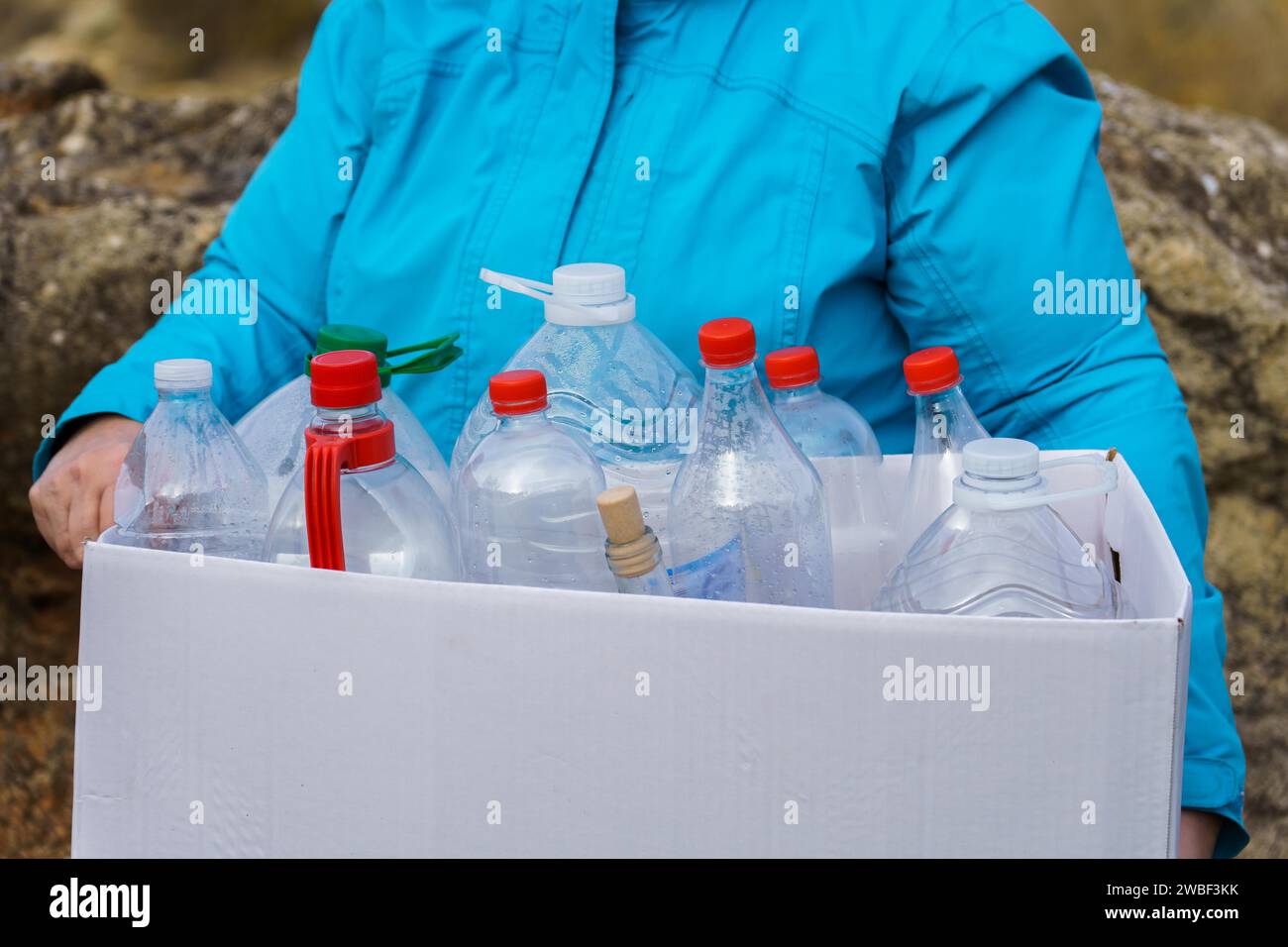 Frau, die eine weiße Pappschachtel voll leerer Plastikflaschen für Recycling, Umweltschutz und Umweltkonzept hält Stockfoto