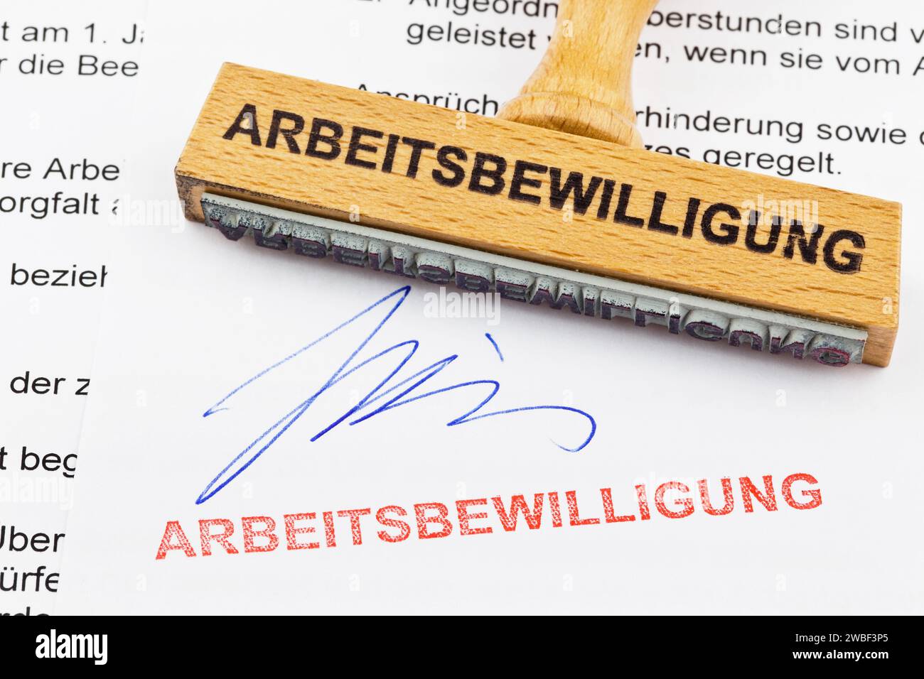 Ein Holzstempel liegt auf einem Dokument. Deutsche Inschrift: Arbeitserlaubnis Stockfoto
