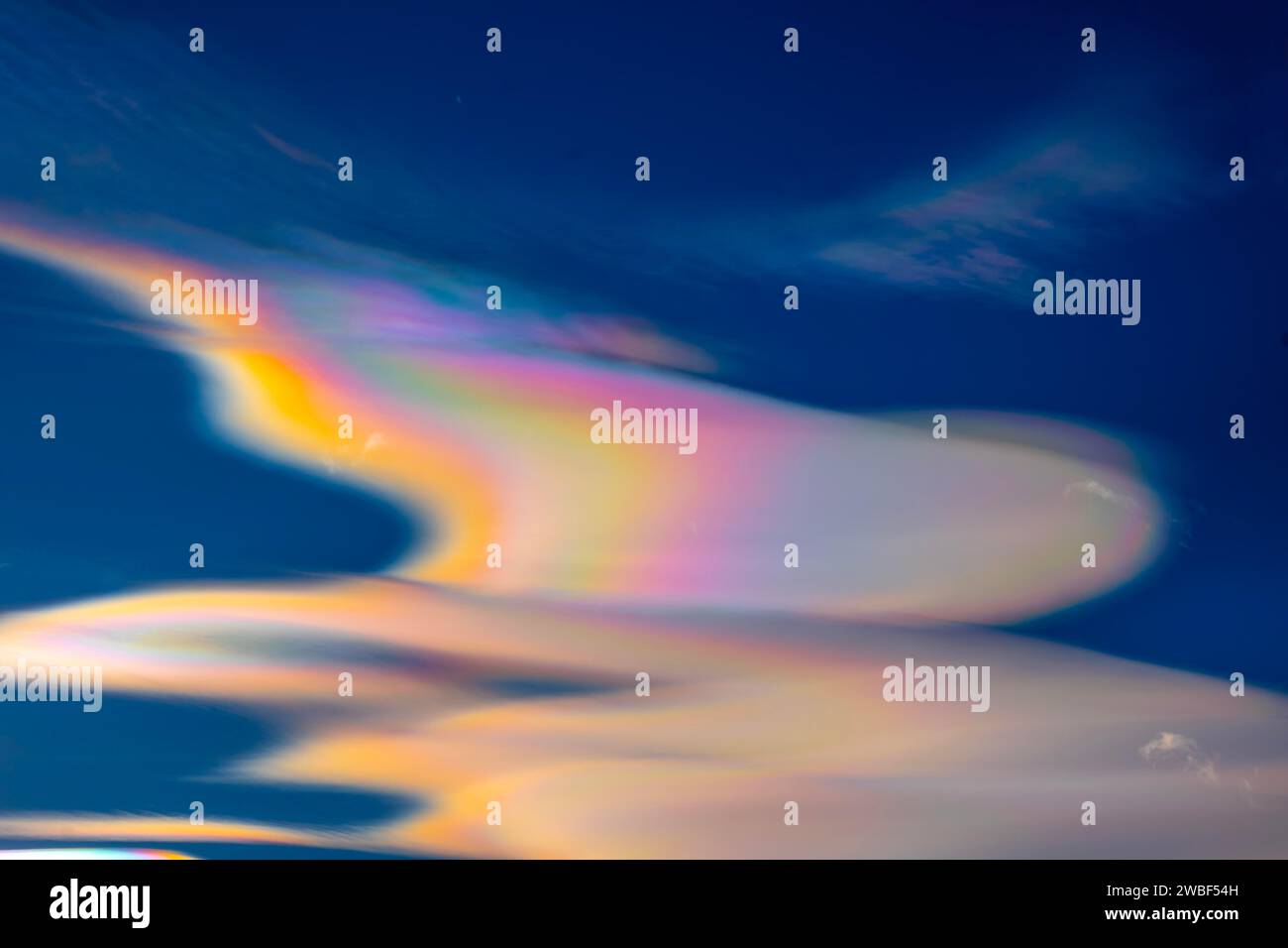 Wunderschöne bunte Regenbogenwolken (Wolkenschillerung) gegen blauen Himmel an einem sonnigen Tag mit Lichteffekt in Lugano, Tessin, Schweiz Stockfoto