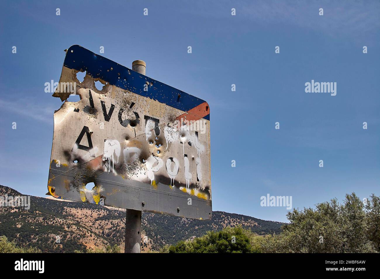 Verwittertes Straßenschild mit Schusslöchern vor einem blauen Himmel und Bäumen im Hintergrund, Anopolis, Sfakia, Westkreta, Kreta, Griechenland Stockfoto