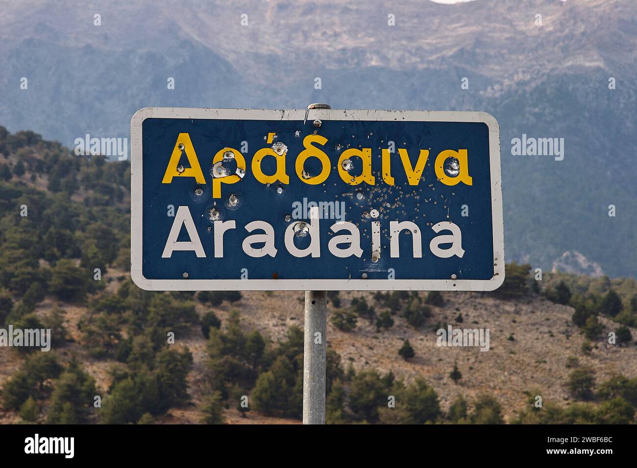 Beschädigtes Straßenschild mit griechischer und lateinischer Schrift vor einer Berglandschaft, Aradena-Schlucht, Aradena, Sfakia, Kreta, Griechenland Stockfoto