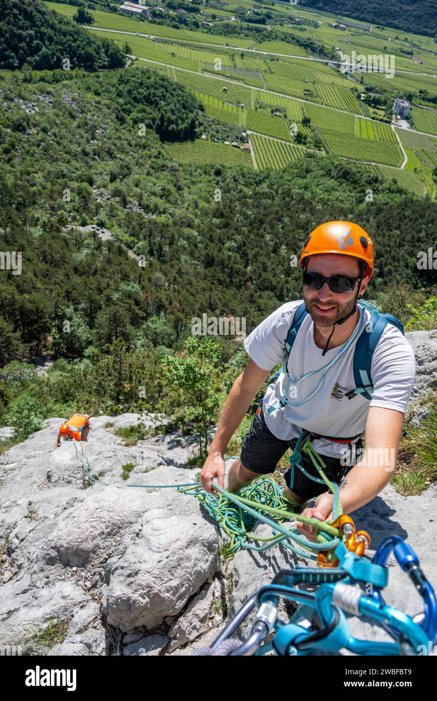 Ein Bergsteiger mit Helm und Sicherheitsausrüstung klettern auf einem Felsen, alpines Klettern mit Seil, Arco, Italien, KI generiert Stockfoto