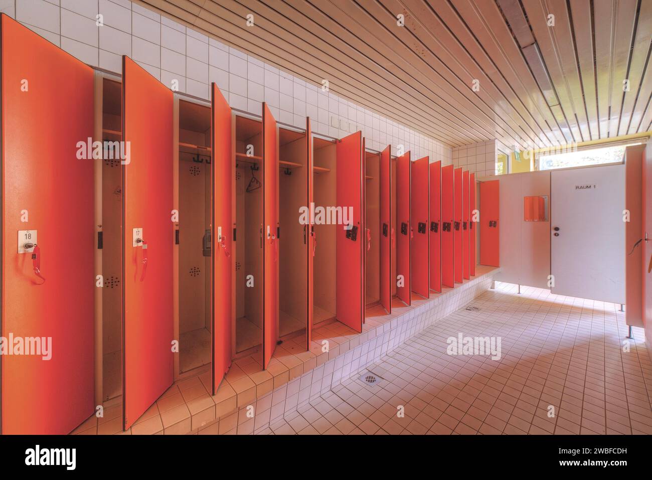 Eine Reihe roter Umkleidekabinen in einem sauberen, leeren Raum, Bad am Park, Lost Place, Essen, Nordrhein-Westfalen, Deutschland Stockfoto