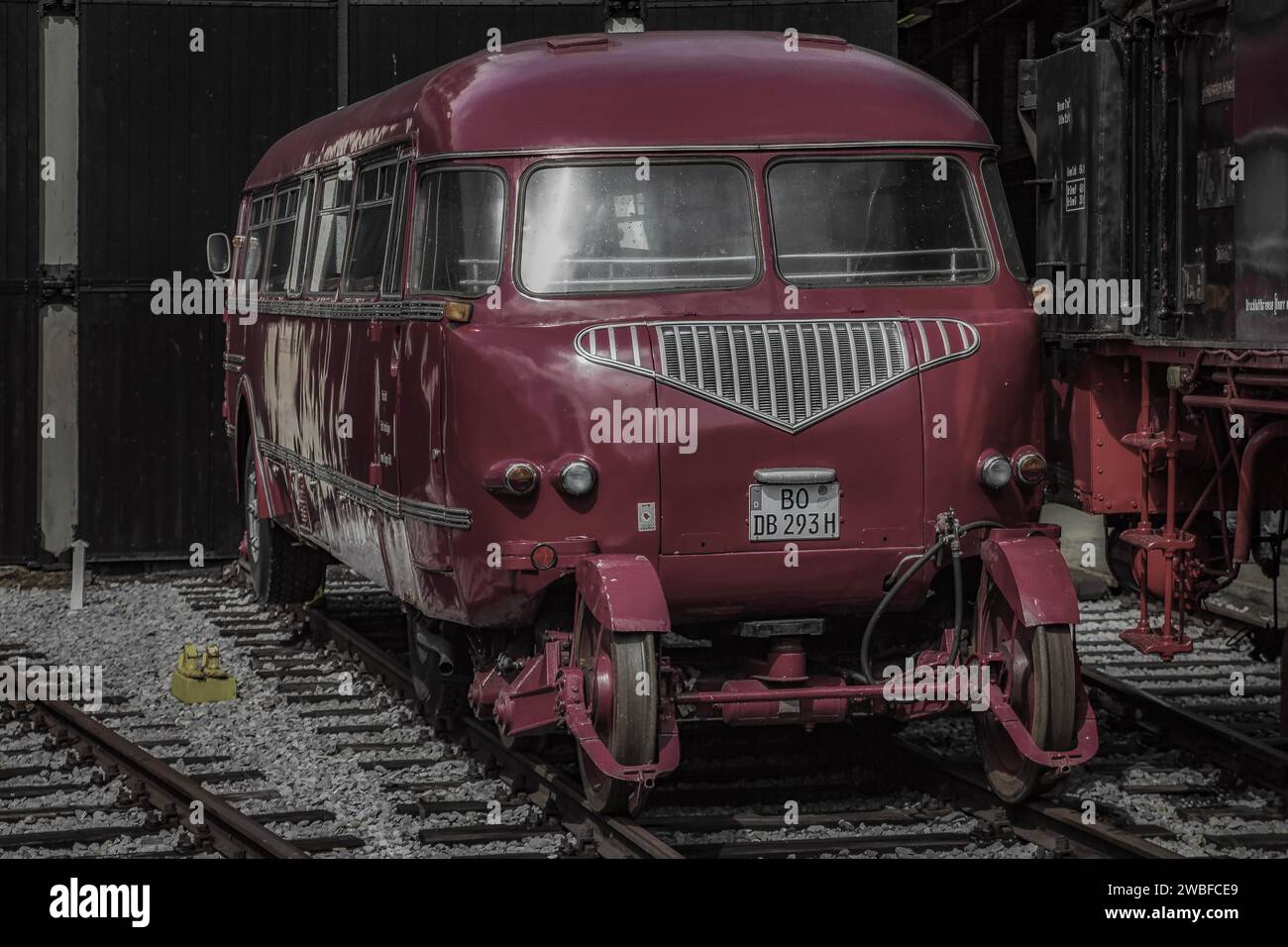 Ein roter Oldtimerbus parkt auf Bahngleisen in einem Museum, Bahnbetriebswerk Dahlhausen, Lost Place, Dahlhausen, Bochum, Nordrhein-Westfalen, Deutschland Stockfoto