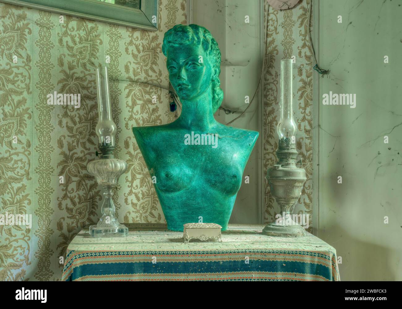 Eine grüne Büste zwischen zwei Kerzenleuchtern auf einem Tisch vor einem Fenster, Maison Limmi, Lost Place, Kalken, Laarne, Provinz Ostflandern, Belgien Stockfoto Eine grüne Büste zwischen zwei Kerzenleuchtern auf einem Tisch vor einem Fenster, Maison Limmi, Lost Place, Kalken, Laarne, Provinz Ostflandern, Belgien Stockfoto