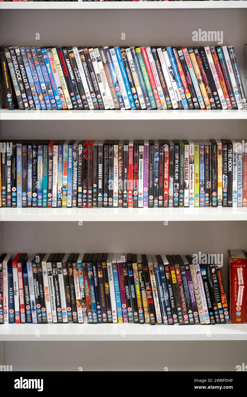 Ein Regal für Wohltätigkeitsorganisationen, in dem drei Reihen gebrauchter DVDs gezeigt werden, die dem Laden zum Wiederverkauf gespendet wurden. Die DVDs werden auf einem Regal angezeigt Stockfoto
