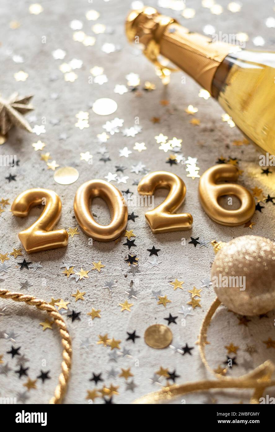 Vertikales goldenes Farbpalettenfoto mit Neujahrsnummern 2026, umgeben von Konfetti und Dekorationen Stockfoto
