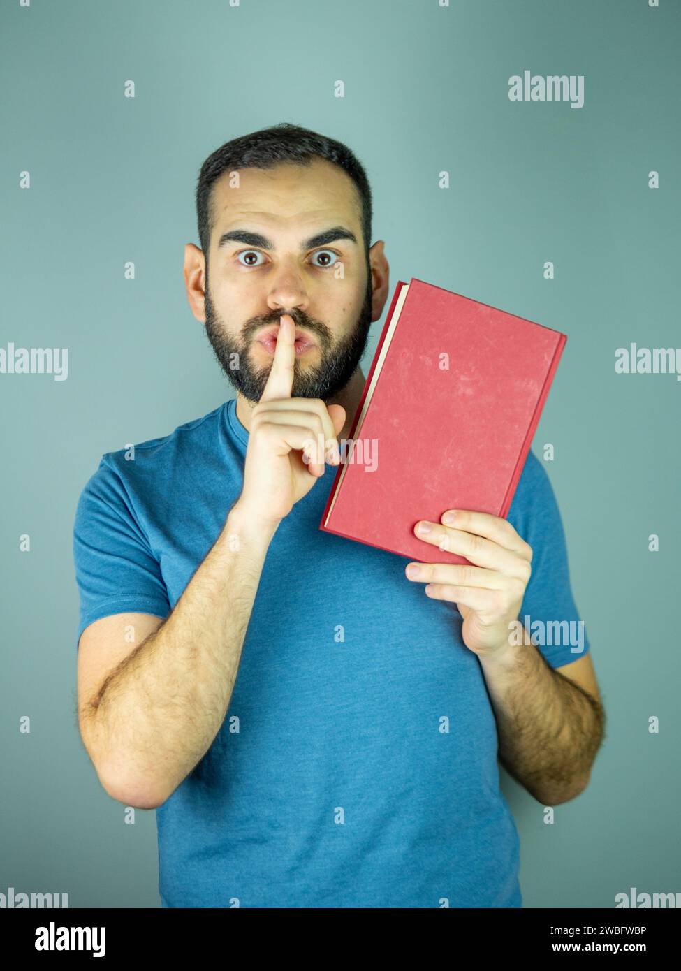 Junger bärtiger Mann, der mit seinem Zeigefinger um Stille bittet Stockfoto