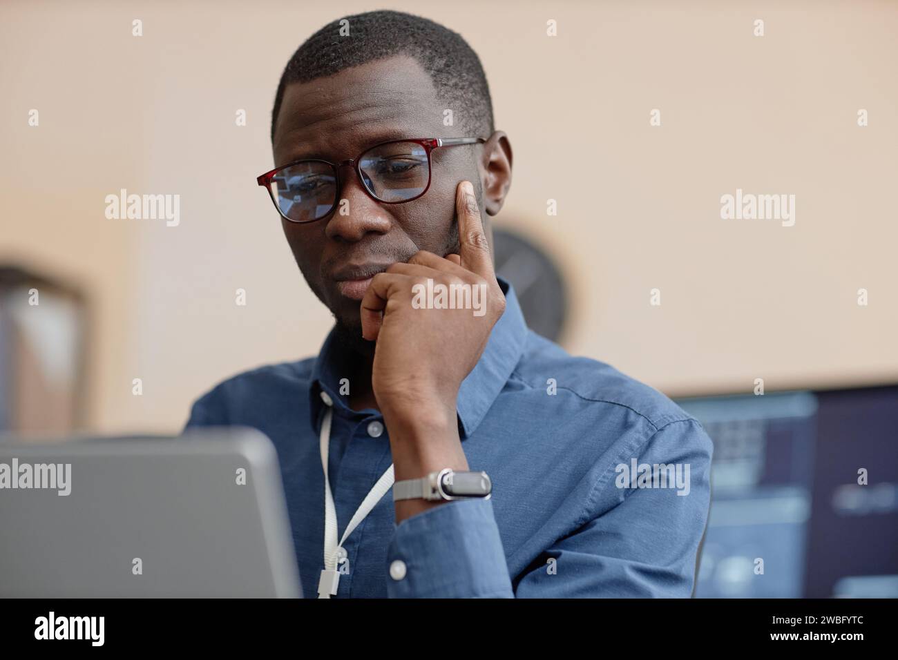 Männlicher IT-Mitarbeiter, der auf den Computerbildschirm hinunterblickt Stockfoto