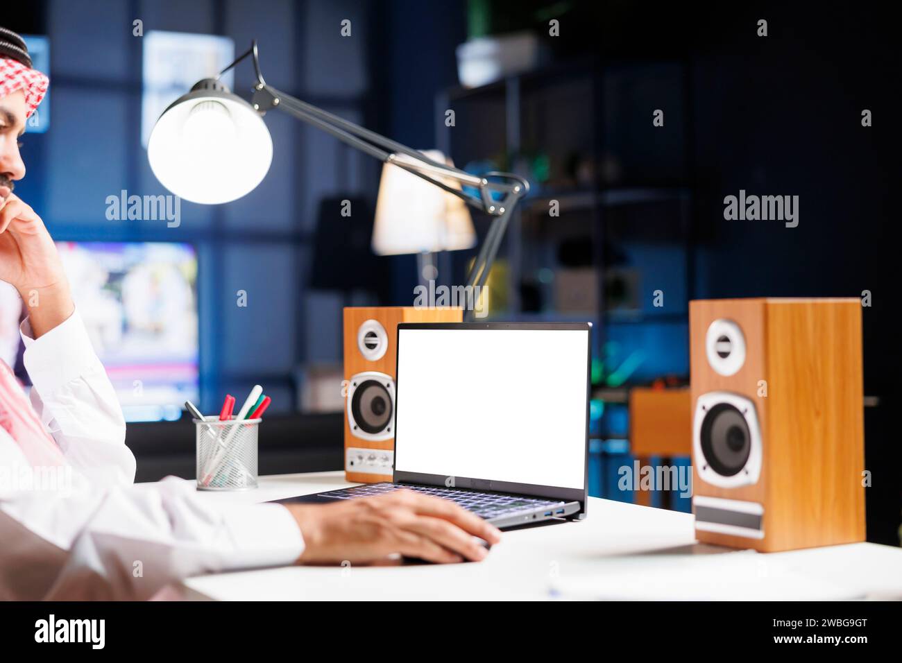 Ein Mann aus dem Nahen Osten benutzt seinen digitalen Laptop, der eine leere Chromakey-Vorlage zeigt. Ein Araber arbeitet an seinem Minicomputer, der einen isolierten weißen Bildschirm hat. Stockfoto