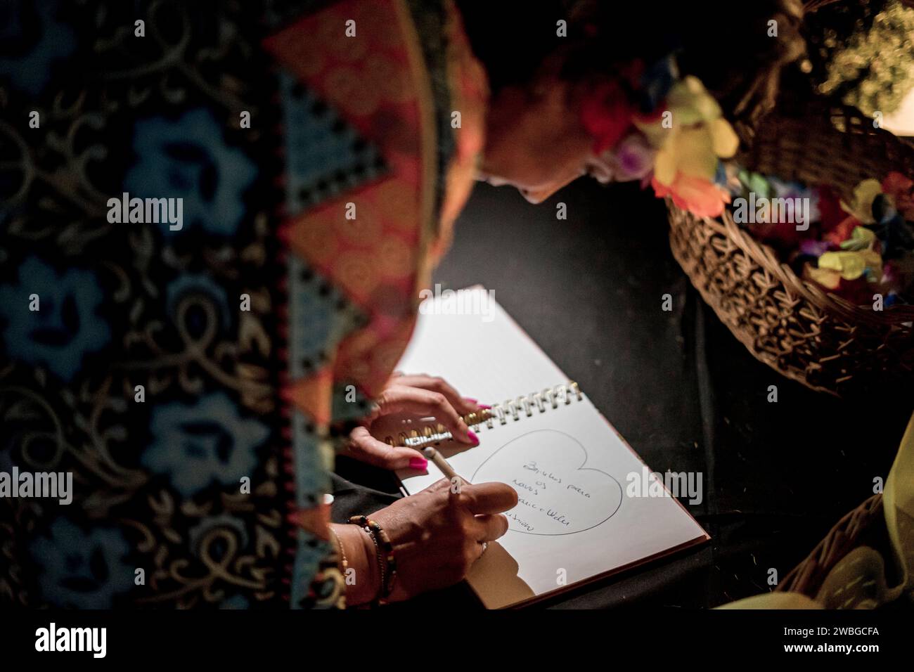 Nicht identifizierbare Frau, die ein Herz in ein Notizbuch schreibt und zeichnet Stockfoto