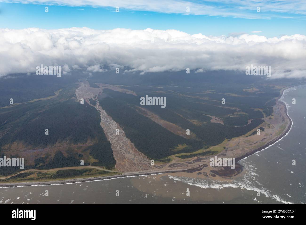 Eine Luftaufnahme zeigt ein Flussdelta, das in den Ozean fließt, umgeben von dichtem Wald, unter einem Himmel mit einer Wolkenschicht. Stockfoto