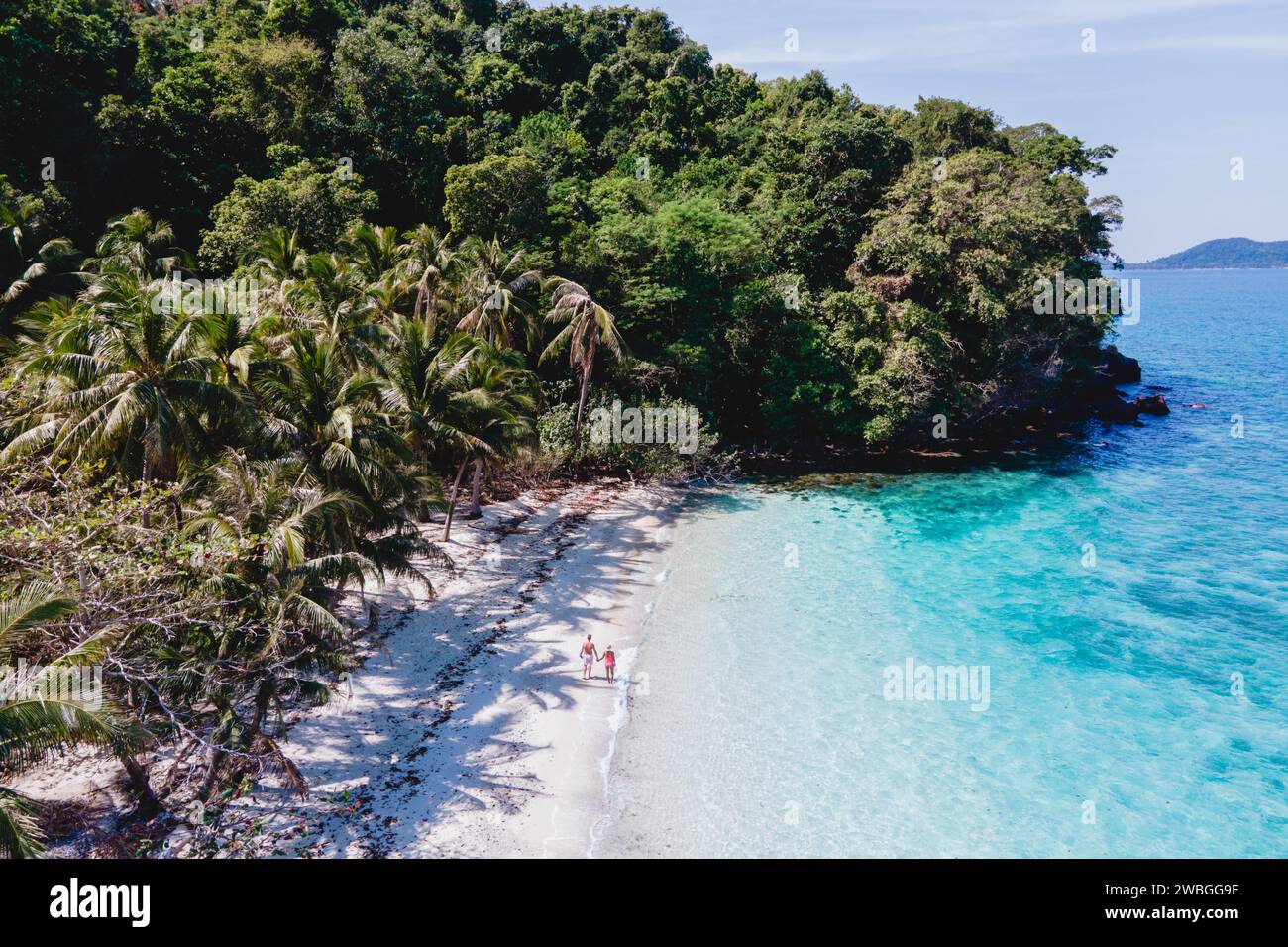 Drohnenblick auf Koh Wai Island trat Thailand. Ein junges Paar Männer und Frauen, die während eines Luxusurlaubs an einem tropischen Strand mit blauem Meer spazieren gehen Stockfoto