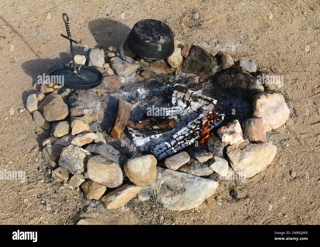 Reinigen des Gusseisens nach dem Kochen im Freien am Feuer Stockfoto