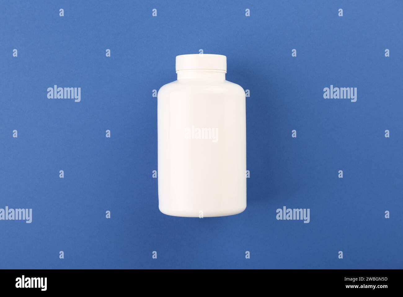 Leere weiße Pillenflasche auf blauem Hintergrund, Draufsicht. Leerzeichen für Text Stockfoto