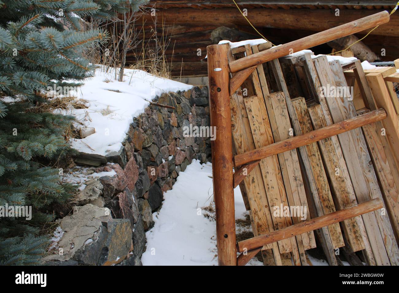 Schneebedeckte Wand mit Holzstapel an der Seite Stockfoto