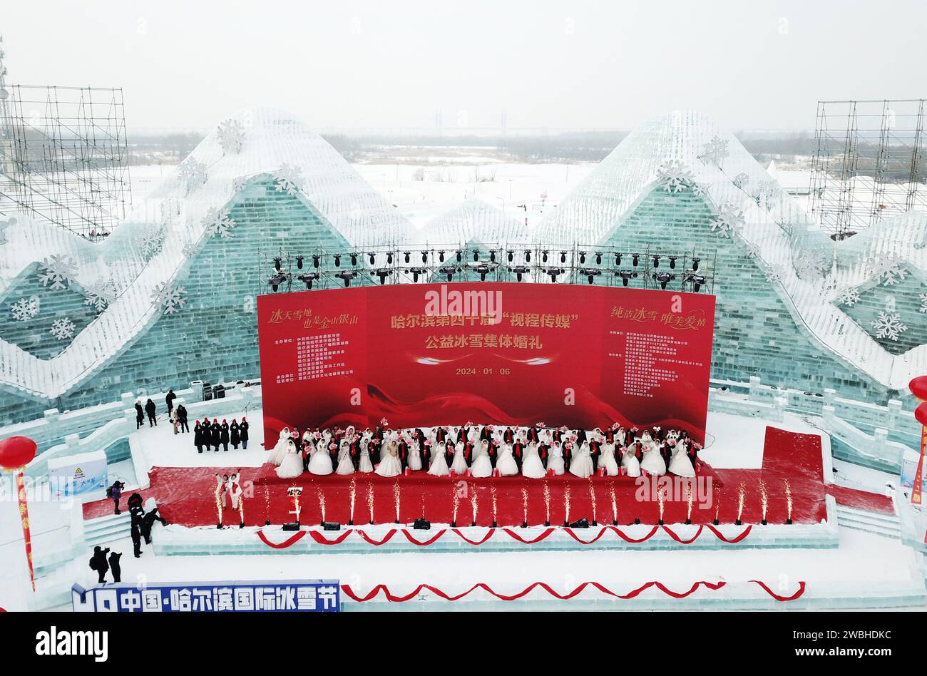 Harbin. Januar 2024. Ein Luftbild der Drohne, aufgenommen am 6. Januar 2024, zeigt Menschen, die an einer Gruppenhochzeit in der Harbin Ice-Snow World in Harbin, nordöstlicher chinesischer Provinz Heilongjiang, teilnehmen. Harbin, die Hauptstadt von Chinas nördlichster Provinz Heilongjiang, ist bekannt als das „Kronjuwel aus Eis und Schnee“ des Landes. Die Stadt hat sich in diesem Winter zu einem der beliebtesten Reiseziele entwickelt. Quelle: Wang Jianwei/Xinhua/Alamy Live News Stockfoto