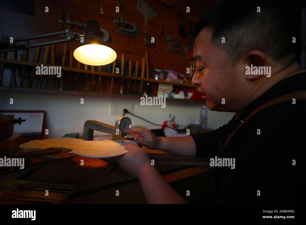 (240111) -- SHENYANG, 11. Januar 2024 (Xinhua) -- Yu Haixu vermisst am 9. Januar 2024 eine Violine in seinem Atelier in Yingkou, nordöstlich Chinas Provinz Liaoning. Yu Haixu ist ein Geigenbauer, der in der Stadt Yingkou im Nordosten Chinas in der Provinz Liaoning arbeitet. Seit seiner Kindheit von seinem Vater beeinflusst, wuchs er allmählich an das anspruchsvolle Geigenbauwerk der Familie an und begann nach dem Studium an der Universität als Geigenbauer zu arbeiten, wobei er sich mit dem Geigenbau sowie anderen Streichinstrumenten wie Viola und Celli beschäftigte. Von Rohstoffen bis hin zu einem feinen Instrument, jede handgefertigte Violine, Bratsche Stockfoto