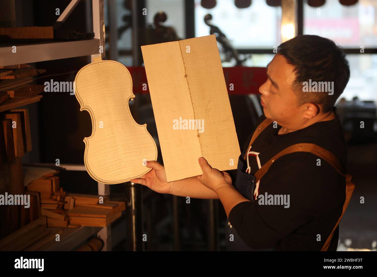 (240111) -- SHENYANG, 11. Januar 2024 (Xinhua) -- Yu Haixu spielt am 9. Januar 2024 in seinem Atelier in Yingkou, nordöstlicher Provinz Liaoning, Violine. Yu Haixu ist ein Geigenbauer, der in der Stadt Yingkou im Nordosten Chinas in der Provinz Liaoning arbeitet. Seit seiner Kindheit von seinem Vater beeinflusst, wuchs er allmählich an das anspruchsvolle Geigenbauwerk der Familie an und begann nach dem Studium an der Universität als Geigenbauer zu arbeiten, wobei er sich mit dem Geigenbau sowie anderen Streichinstrumenten wie Viola und Celli beschäftigte. Von Rohstoffen bis hin zu einem feinen Instrument, jede handgefertigte Violine, Bratsche oder Stockfoto