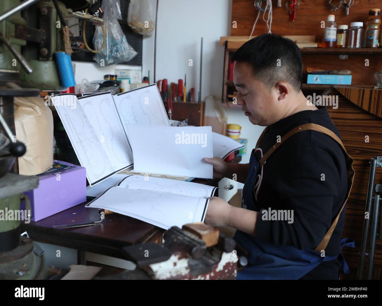 (240111) -- SHENYANG, 11. Januar 2024 (Xinhua) -- Yu Haixu sieht sich am 9. Januar 2024 in seinem Atelier in Yingkou, nordöstlicher Provinz Liaoning, Geigenbaupläne an. Yu Haixu ist ein Geigenbauer, der in der Stadt Yingkou im Nordosten Chinas in der Provinz Liaoning arbeitet. Seit seiner Kindheit von seinem Vater beeinflusst, wuchs er allmählich an das anspruchsvolle Geigenbauwerk der Familie an und begann nach dem Studium an der Universität als Geigenbauer zu arbeiten, wobei er sich mit dem Geigenbau sowie anderen Streichinstrumenten wie Viola und Celli beschäftigte. Von Rohstoffen bis hin zu einem feinen Instrument, jede handgefertigte Gambe Stockfoto