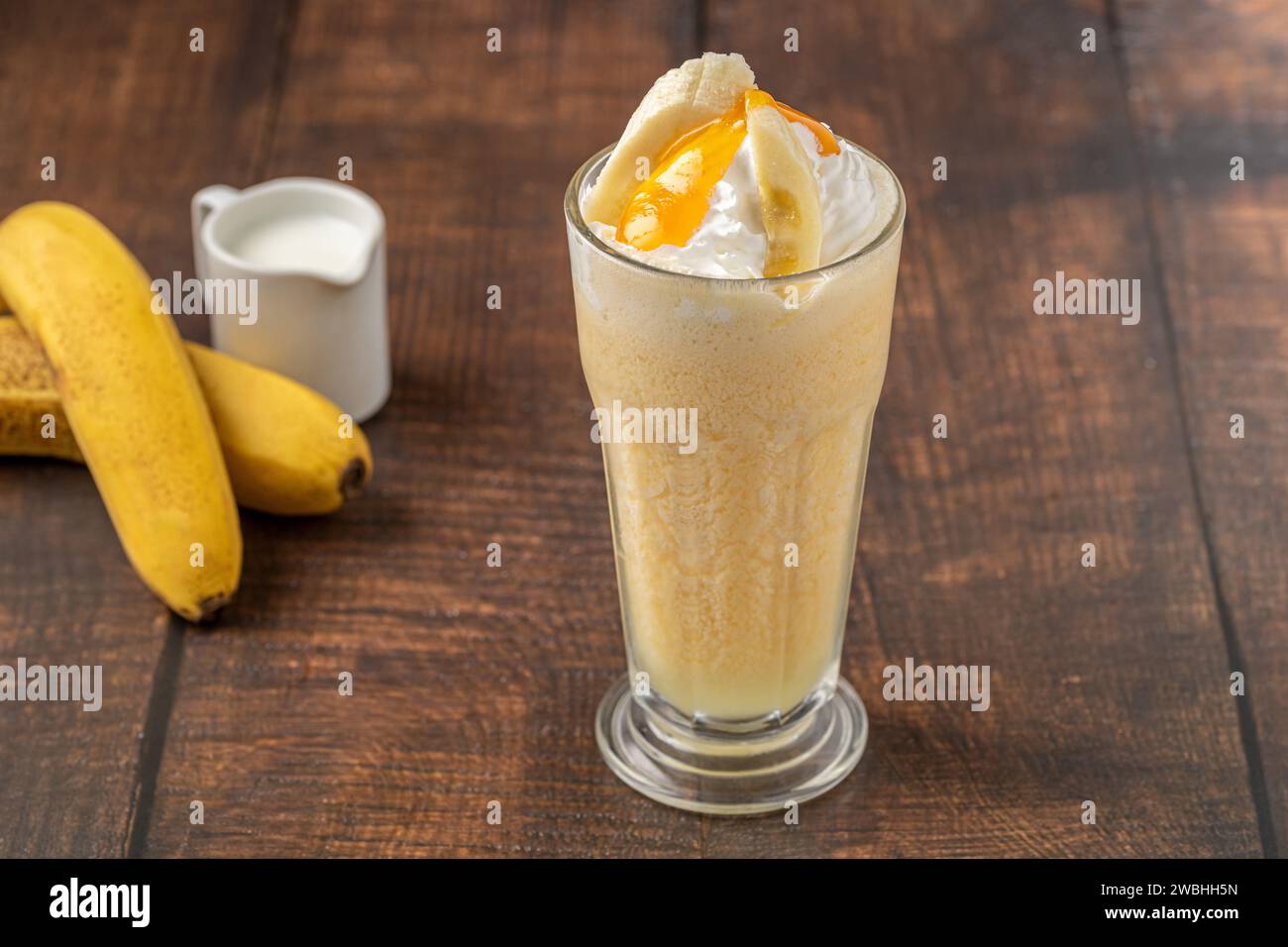 Bananen-Smoothie in Glasbecher auf Holztisch Stockfoto
