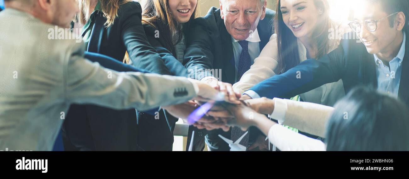 Ein vielfältiges Geschäftsteam vereint sich in einem hellen Büro zu einem Zeichen der Einheit und Zusammenarbeit. Stockfoto