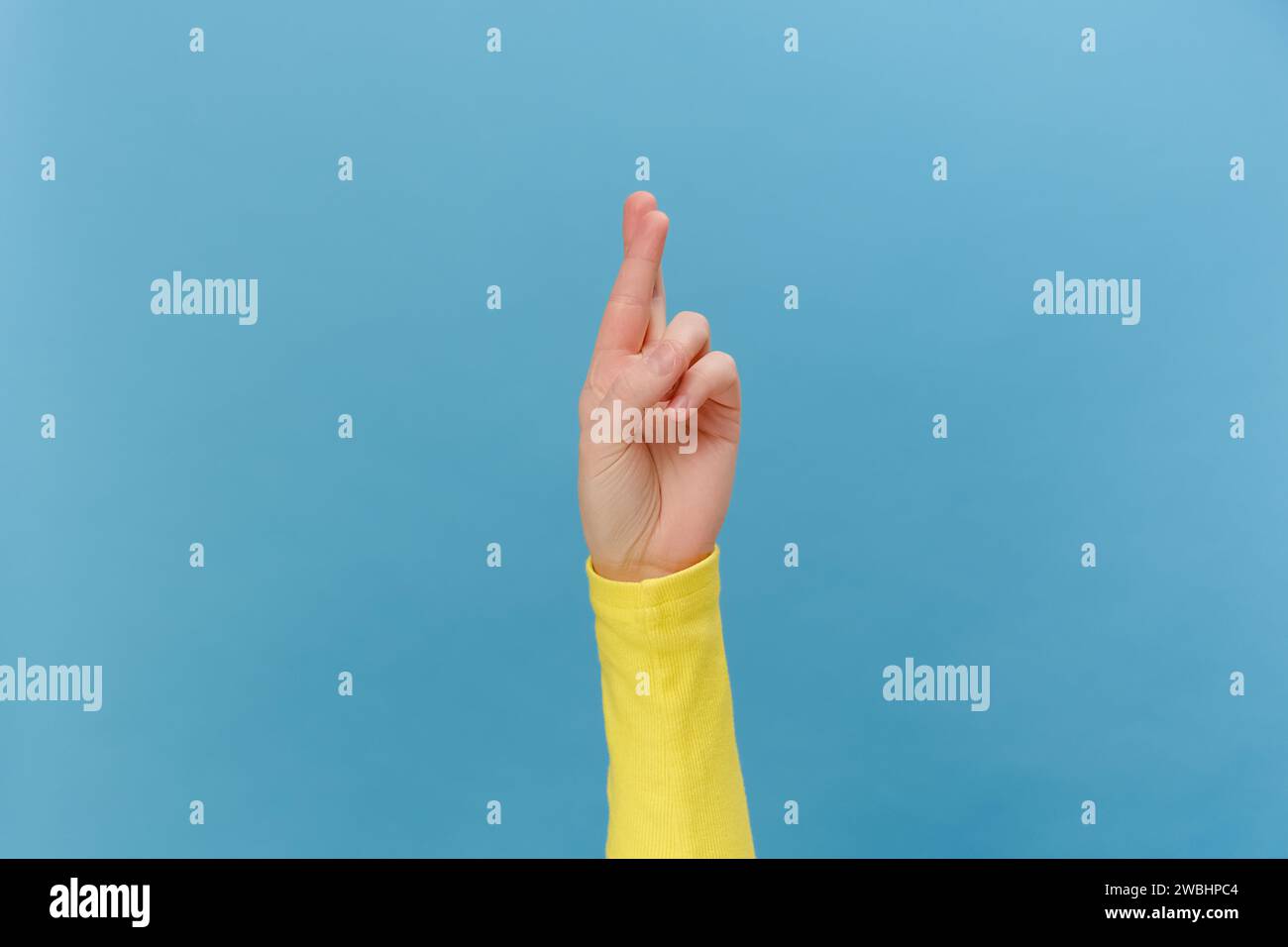 Nahaufnahme von weiblichen Händen, die mit gekreuzten Fingern beten, hofft auf ein wunderbares gutes Ergebnis, isoliert über blauem Studiohintergrund mit Kopierraum. Body langu Stockfoto