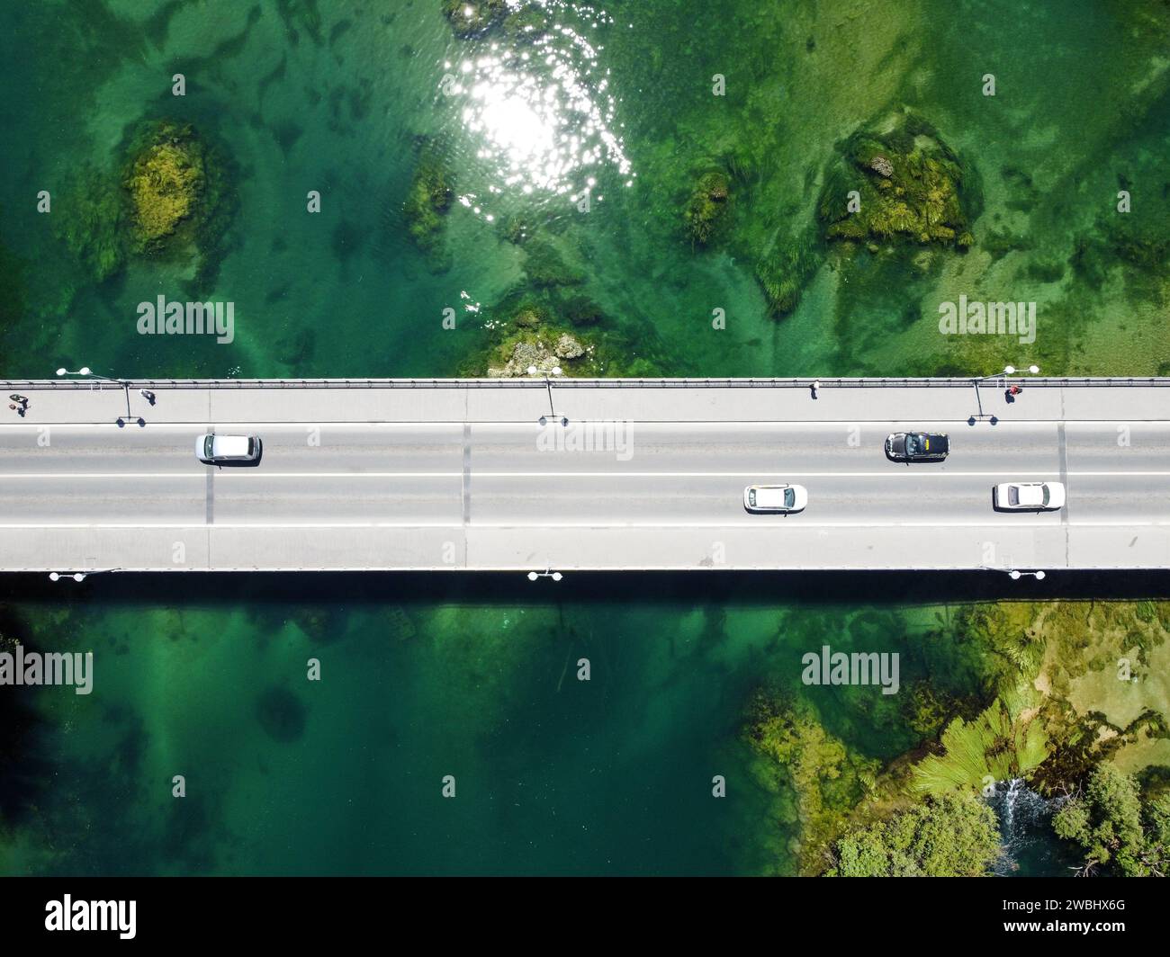 Brücke über dem wunderschönen grünen Fluss, Blick auf die Drohne aus der Luft. Autos und Fußgänger, die sich auf Asphaltbrücke bewegen, Blick von oben. Transport. Betonbrücke Stockfoto